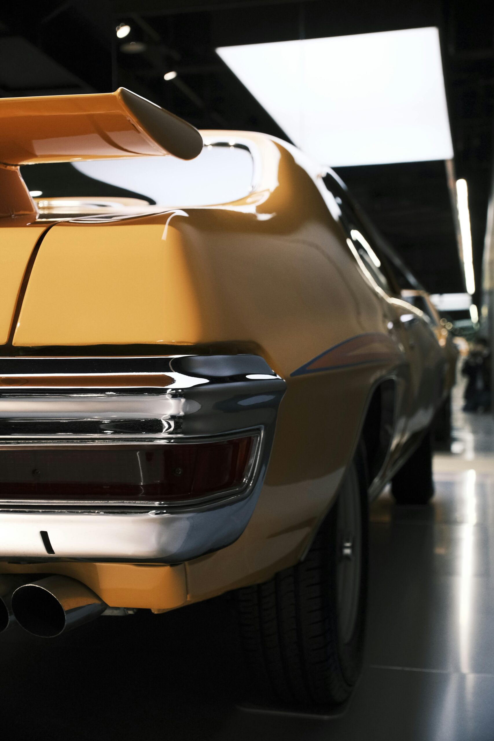 Close-up of a yellow vintage car in a dimly lit indoor setting, showcasing its iconic rear design.